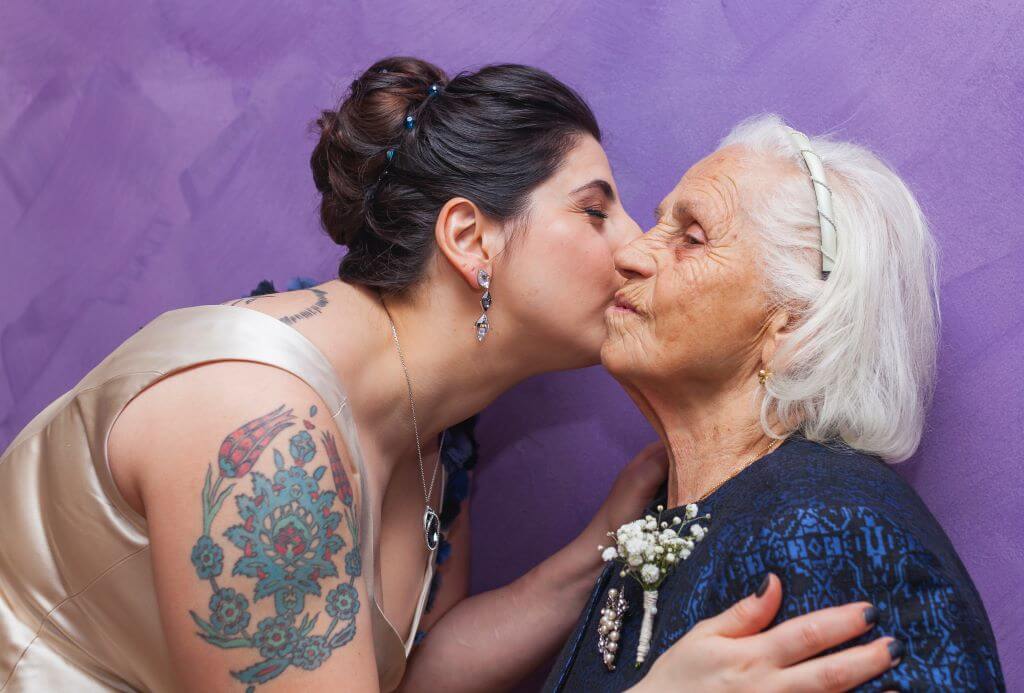 Pflegekraft küsst Seniorin auf die Wange